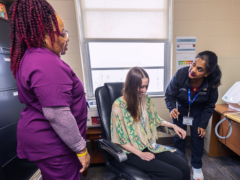 Gaarmel Funches (left), project manager, and researchers Aubrey Rochelle (seated) and Shukla Faruque simulate a pin prick in preparation for the pain disparities study.
